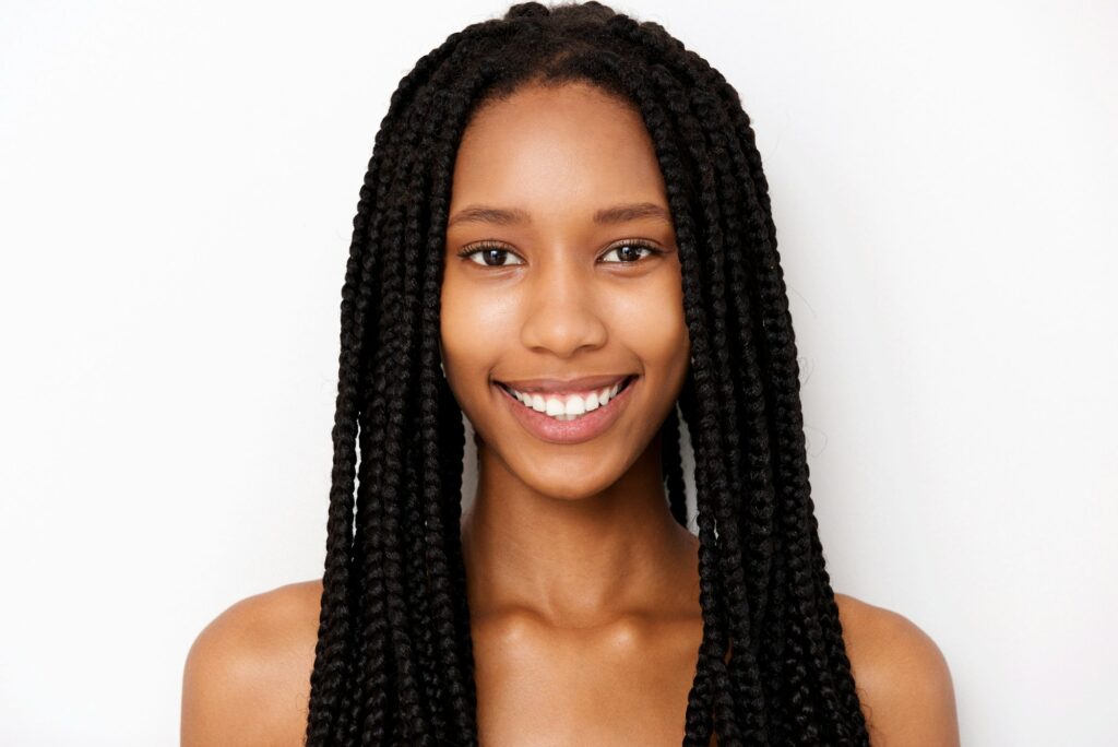 Close up smiling african american young woman with braids on white background